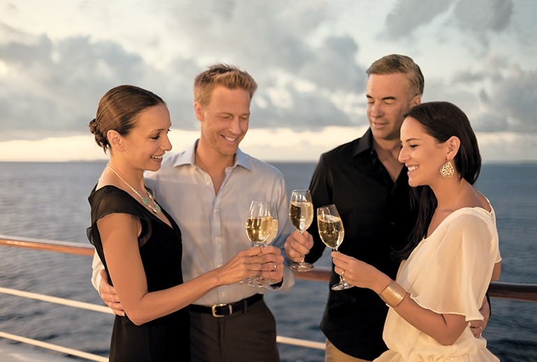 Two couples enjoying a glass of wine at sunset on deck.