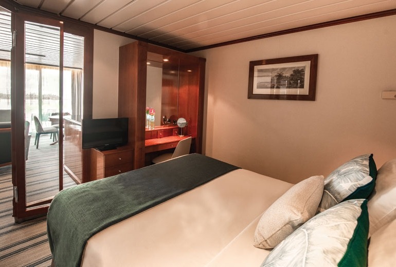 Bedroom view of Owner's Suite #7002 aboard the luxury small-shop m/s Paul Gauguin