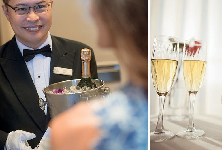 A butler arrives at the stateroom door with a bucket of champagne.